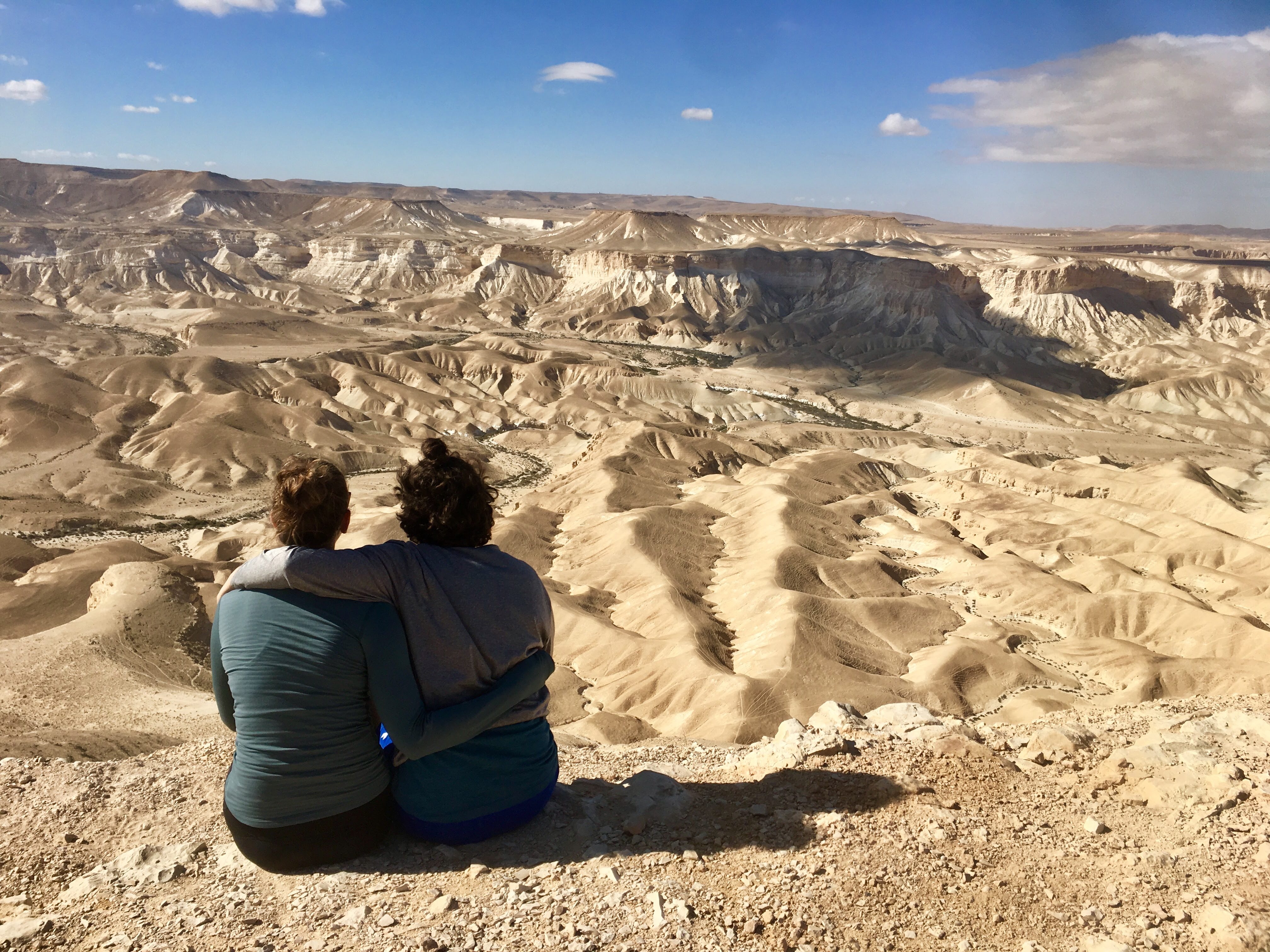 Two people sitting in the desert overlooking the landscape