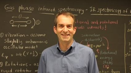 Darren G. Hamilton, smiling in front of a blackboard